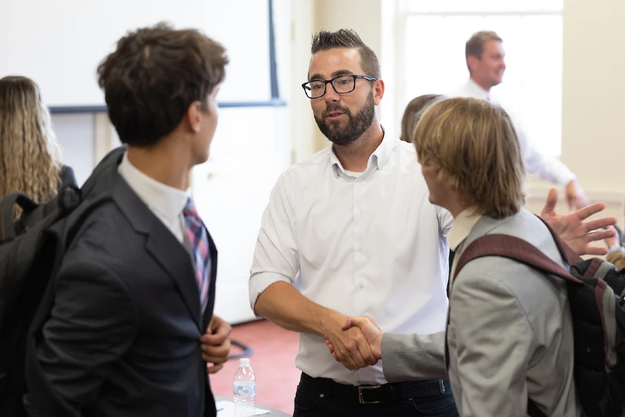prime administrator shaking hands with two students