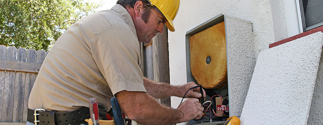 A repairman wearing a hard hat leans over the machinery