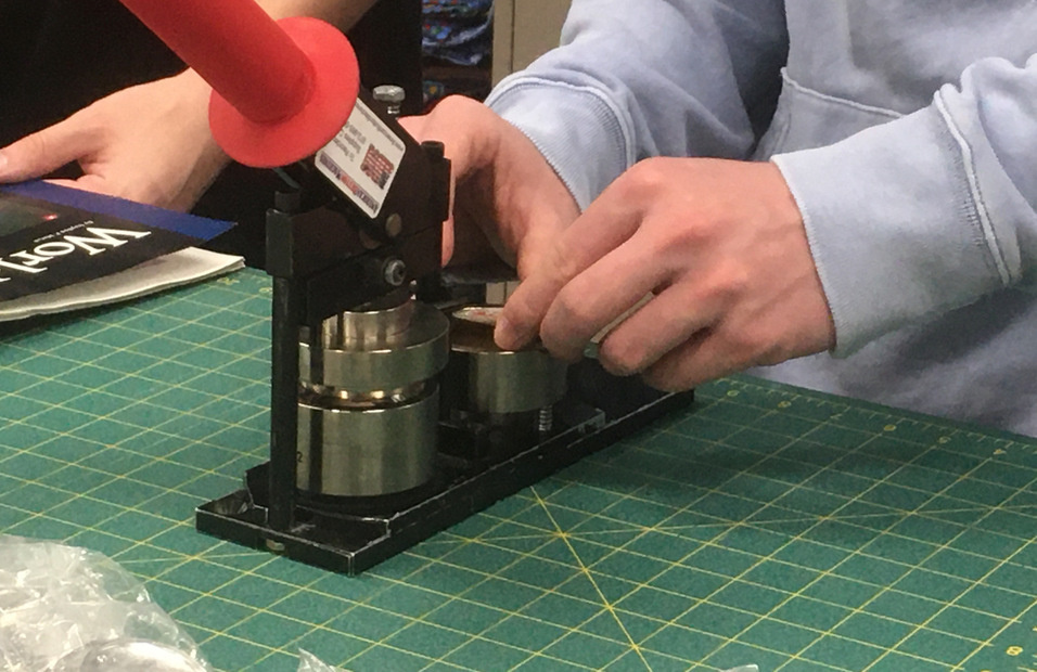 a student uses a button making machine