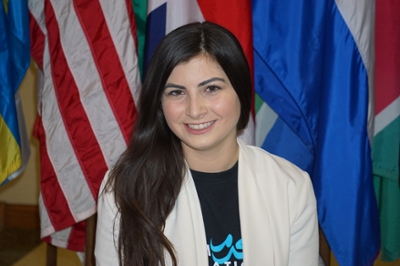 award winner smiles in front of flags