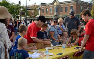 a student volunteer helps a child use chopsticks