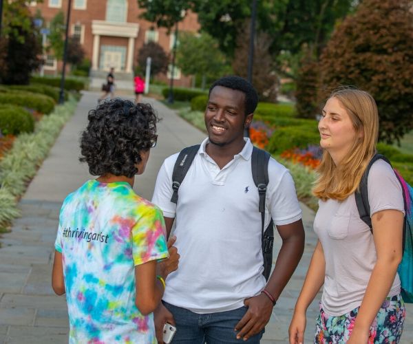 three students talking with eachother on Miami's campus