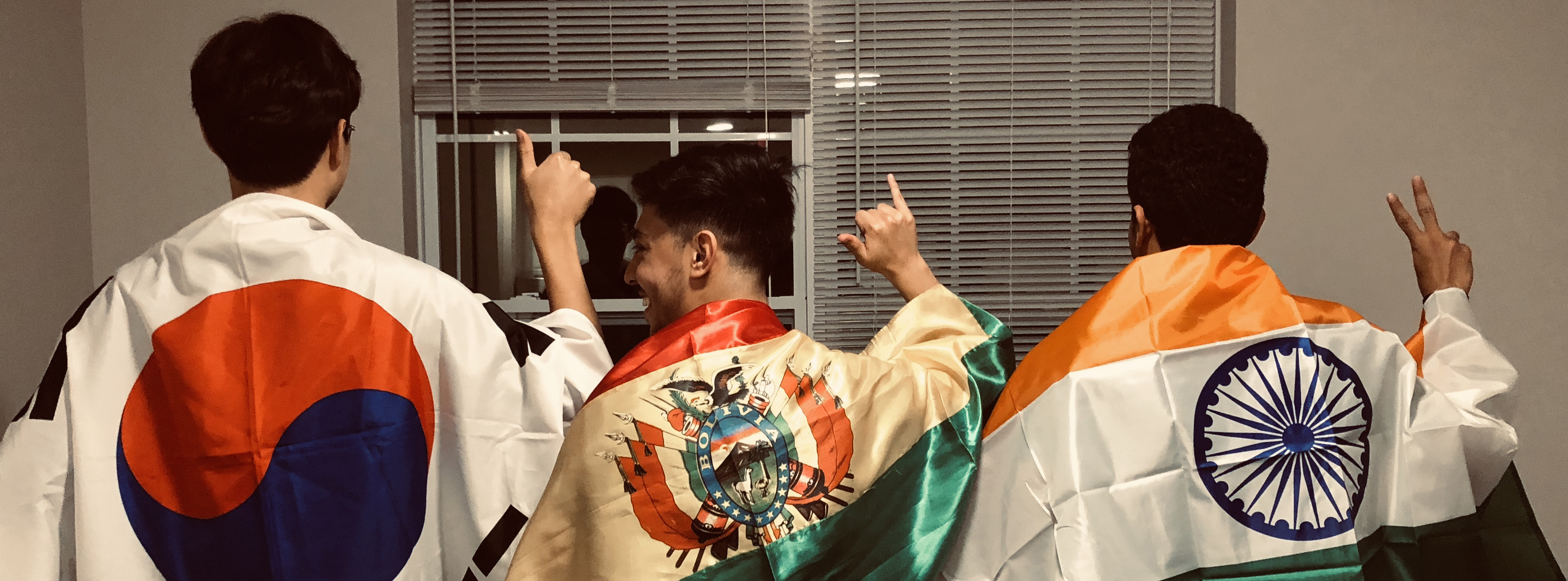 Three male students wearing their home country flags