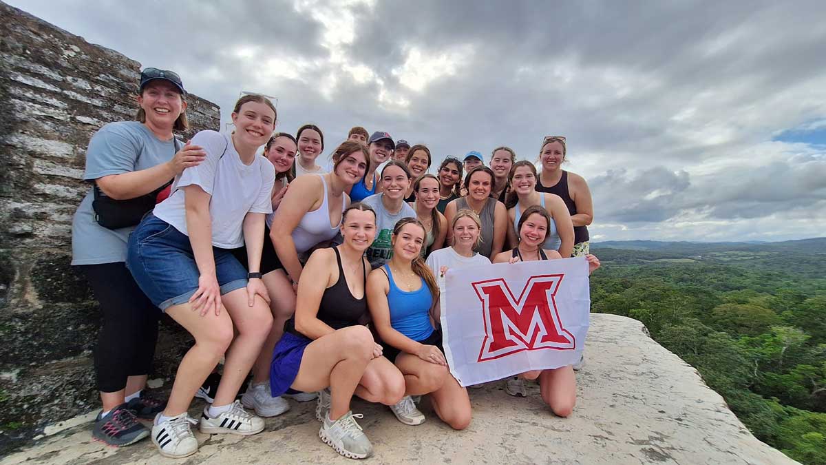 students posing with a flag with the Miami University beveled M
