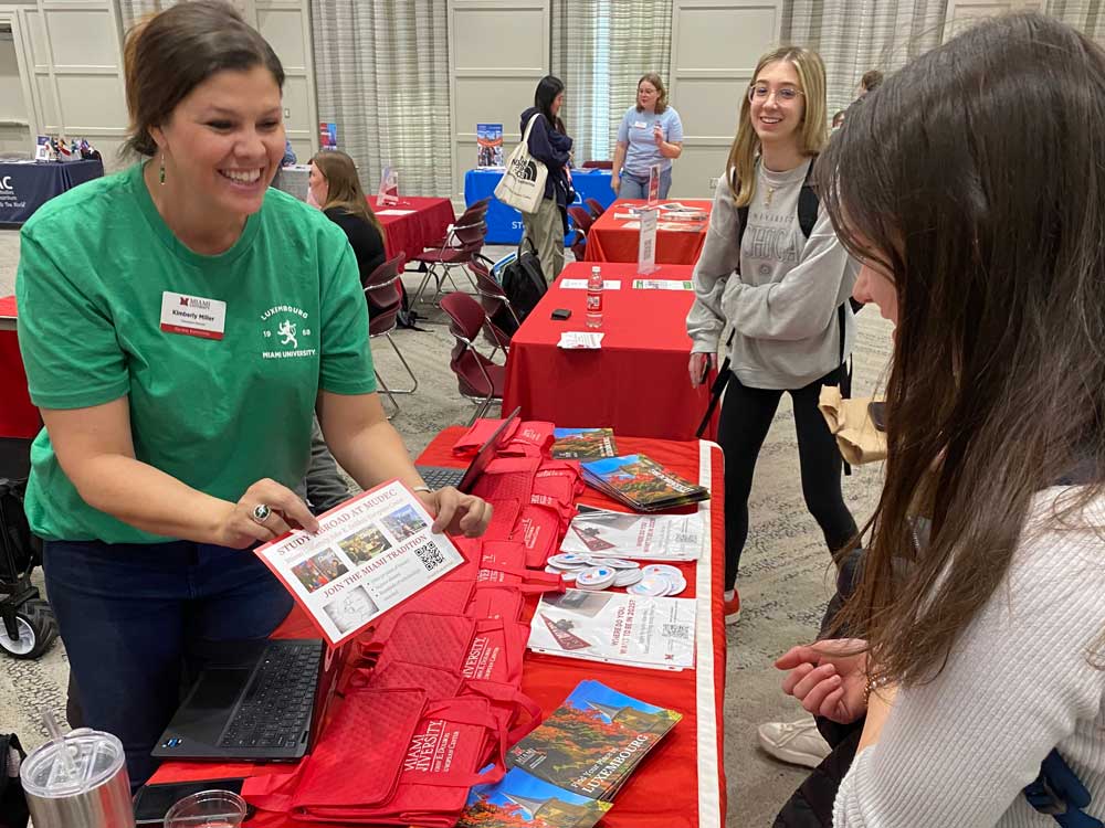 Kimberly Miller speaking with a student while showing them a brochure education abroad opportunities