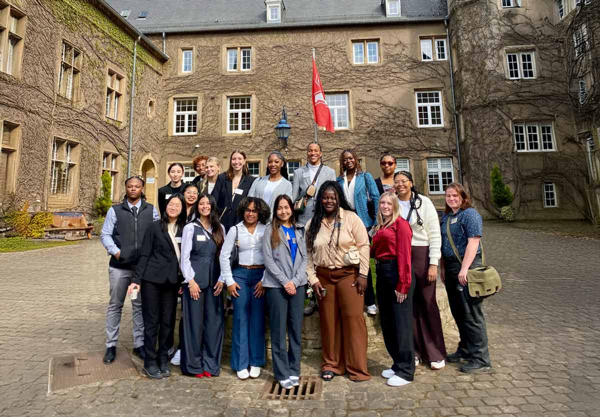 A group of Miami University students pose for a photo in front of the Château de Differdange in Luxembourg, home of the MUDEC campus, on a sunny day.