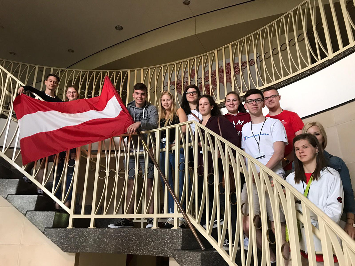 A group of Austrian students display their flag along the stairwell in MacMillan hall