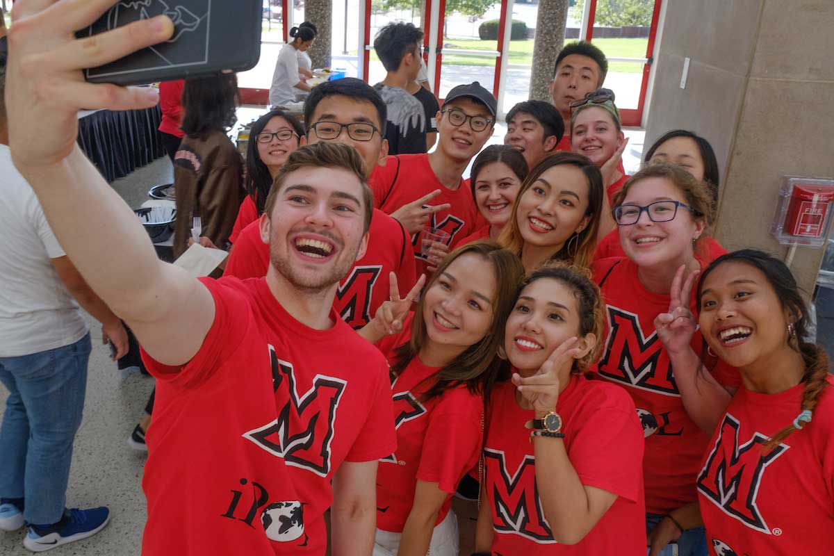 a group of international students taking a picture together with a smartphone