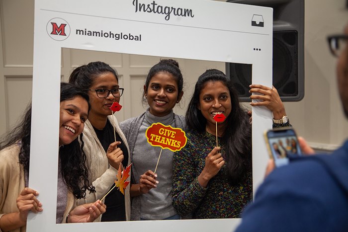 A group of students pose for a photo holding a large Instagram sign