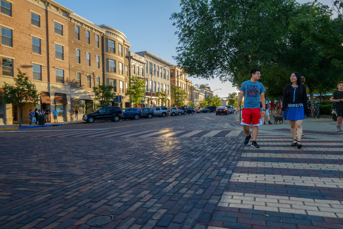 Two students cross the brick street in Uptown Oxford