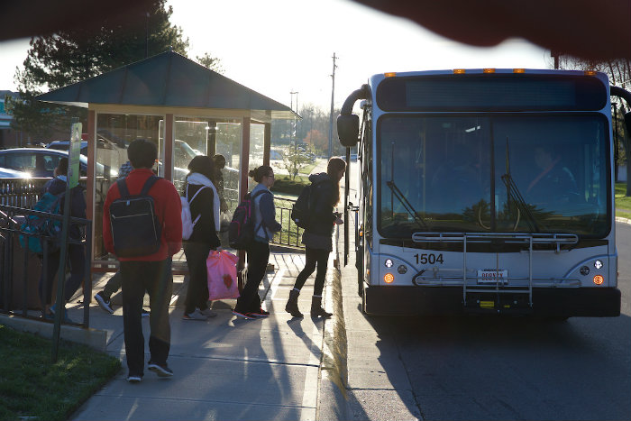Students getting on the bus on a sunny day