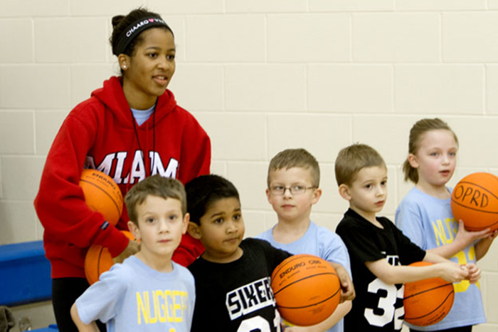 Children play basketball with a Miami student