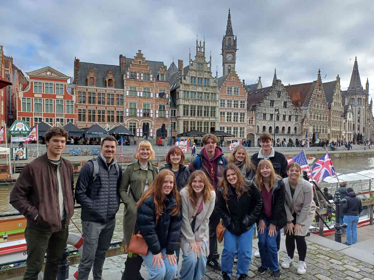 students standing along a river's pier