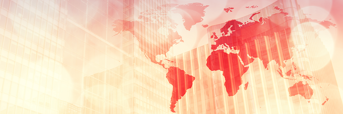 Red world map overlaid on modern glass office buildings in warm red, orange, and yellow tones, representing global business.