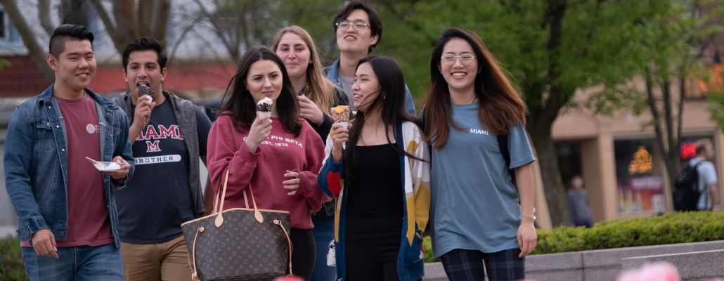 students walking through uptown Oxford eating ice cream cones and smiling