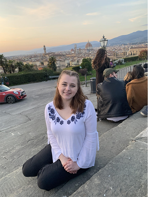 Paige on steps with city visible in background