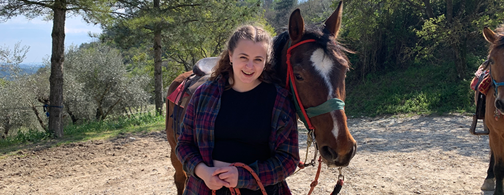 Paige holds the reins and stands next to a horse