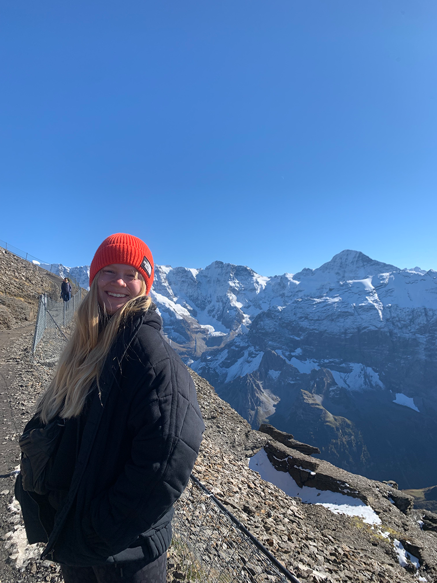 Mary poses during a hike with mountains in background
