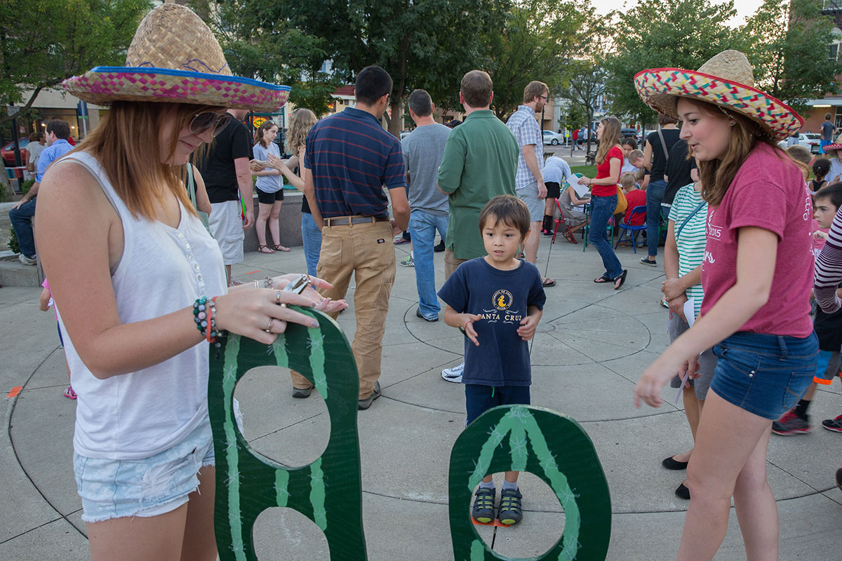 Two young women adjust a cactus game as a child looks on. 