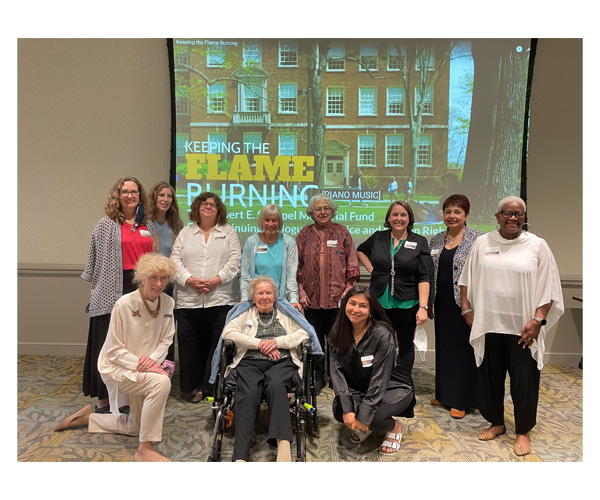 Strippel committee members flank Mrs. Jane Strippel, with the opening of the video onscreen behind them