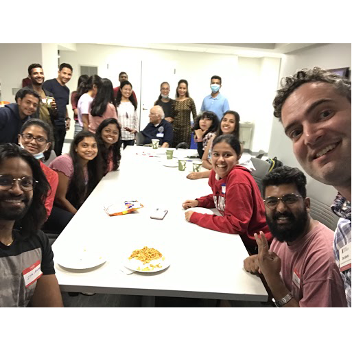 International students seated at an oblong table look toward the camera and smile