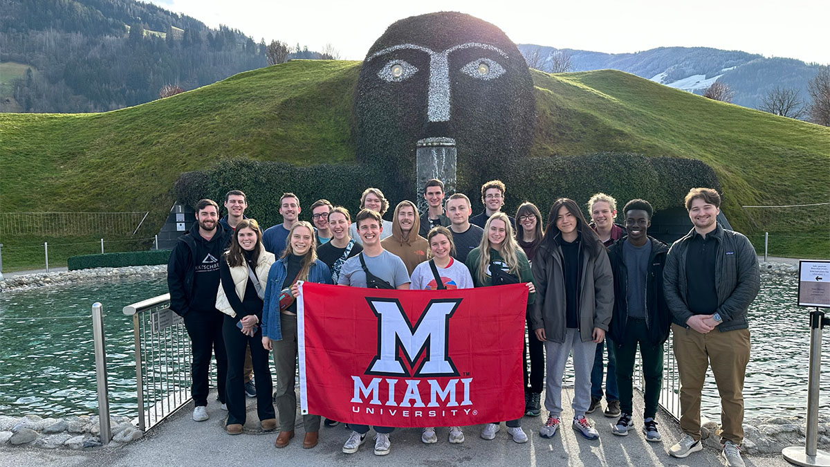 Students pose with an M flag in front of the entrance of Swarovski Museum in Innsbruck, Austria