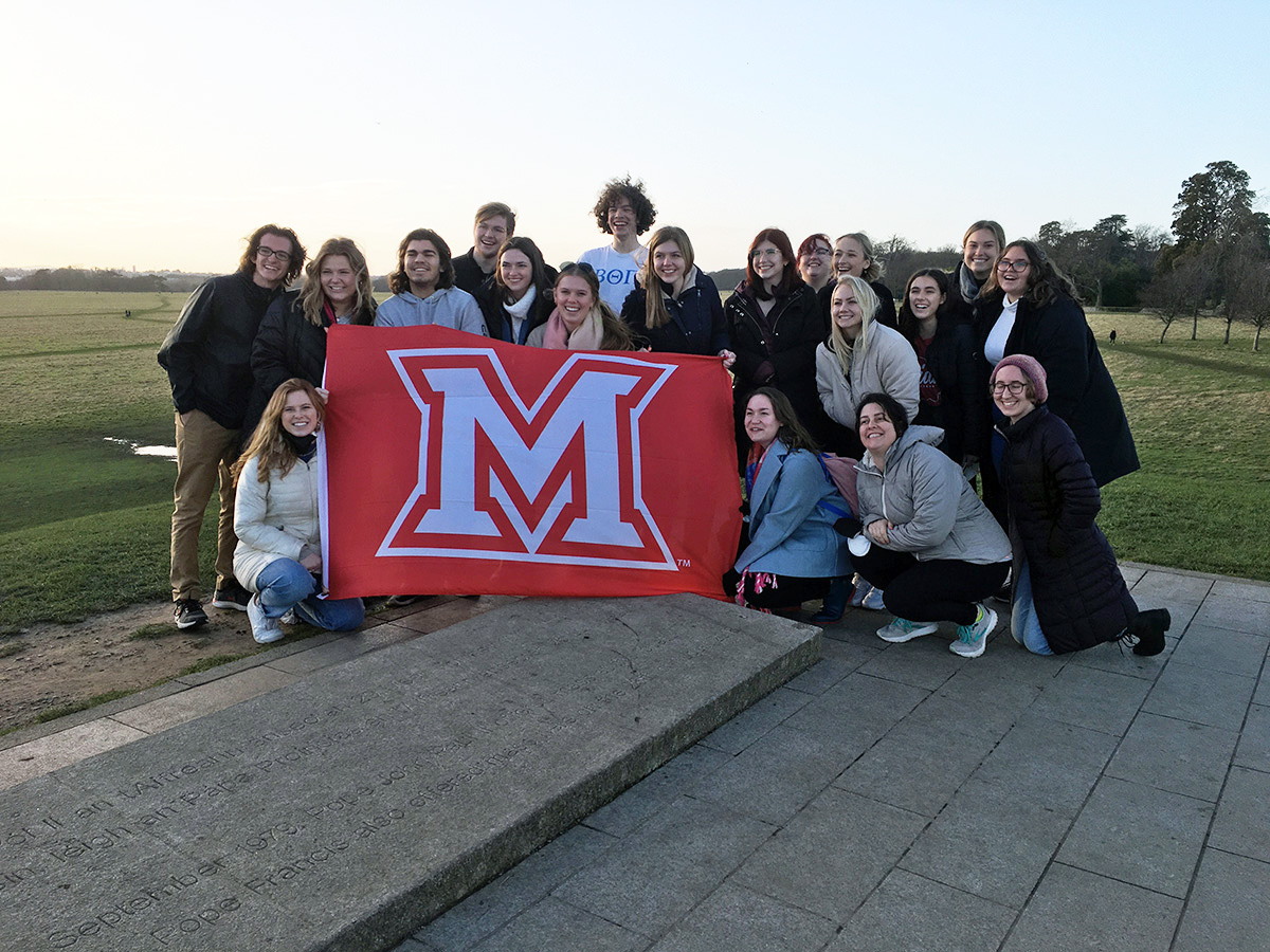 A group of Miami students pose with an M flag in Ireland