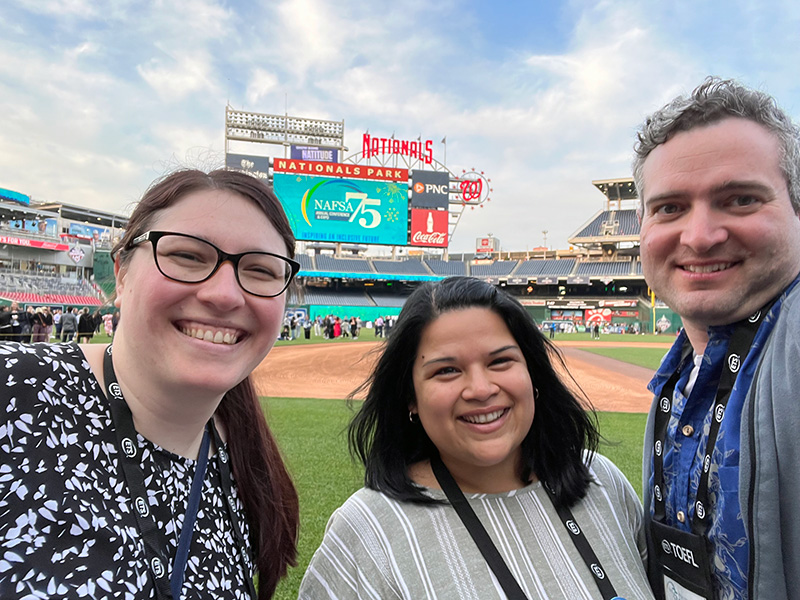 Global Initiatives staff members Maria Potter, Alicia Castillo Shrestha, and Dan Sinetar at a conference outing in a baseball stadium