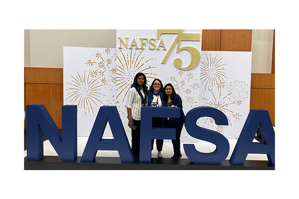 Karla Guinigundo poses with friends in front of NAFSA 75 logo