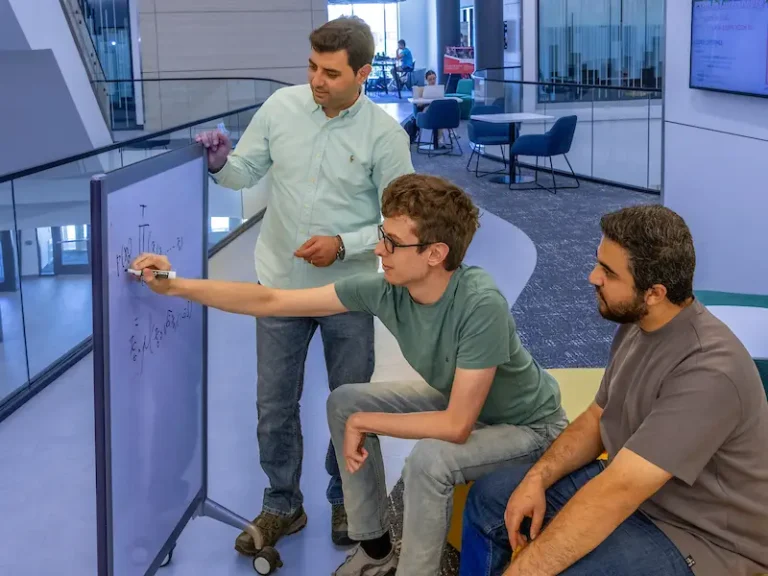 Students solving problems on a whiteboard, engineering. 