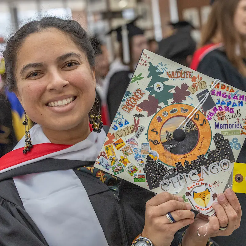 student showing decorative graduation cap with Chicago written on bottom