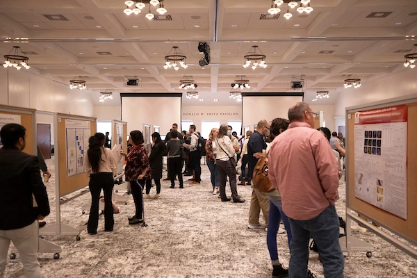 2024 graduate research forum set up with presentation boards and people viewing research in large room