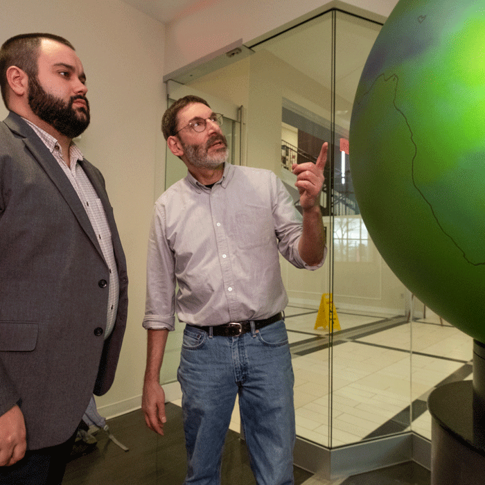Jonathan Levy pointing to a globe and speaking to a student