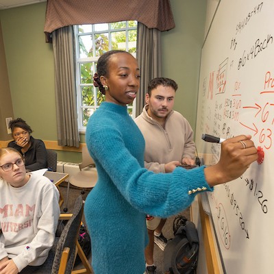 Miami University alum working with students at a white board in a Capstone class