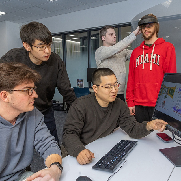 Seated: student Ian Dewey and professor Xianglong Feng. Standing: students Zhaowen Chen, Camden Amata, Evan Patterson. The team tests a VR headset.