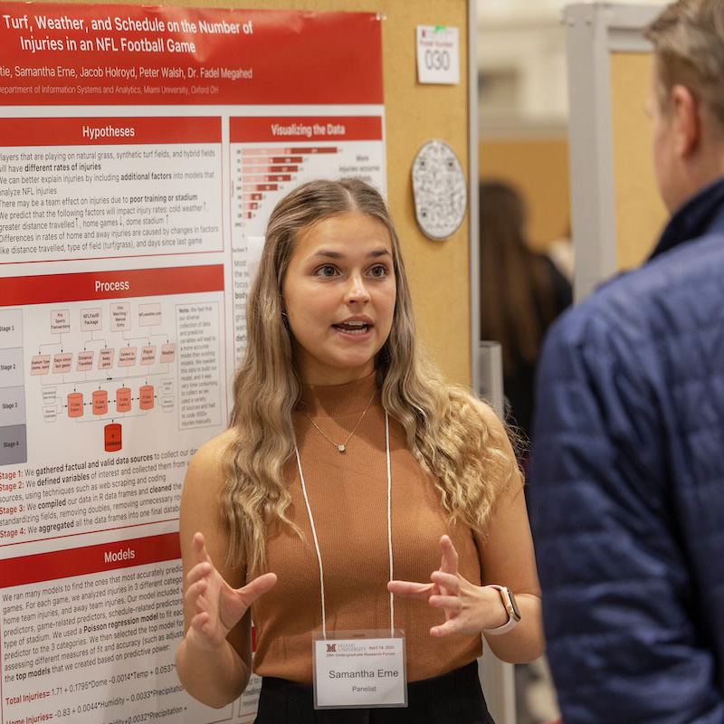 Miami undergraduate students presents her research poster to a visitor at the annual Undergraduate Research Forum