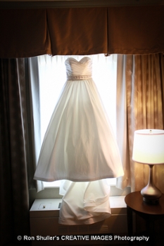 A bride's dress framed by a window and light spilling in to the room.
