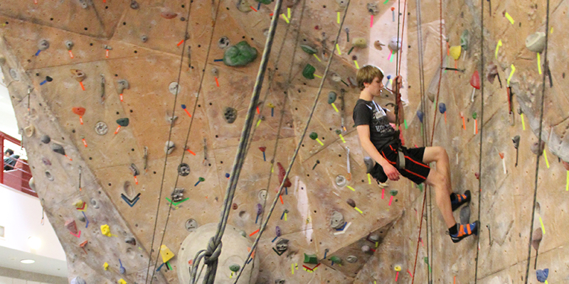 Student climbing up the rock wall.
