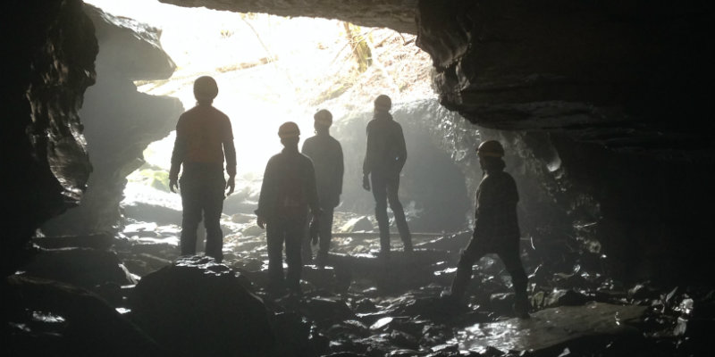 Group standing in cave, staring out towards the light in an epic manner