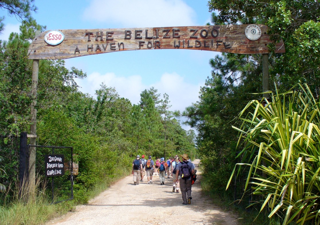 people walking through belize zoo sign