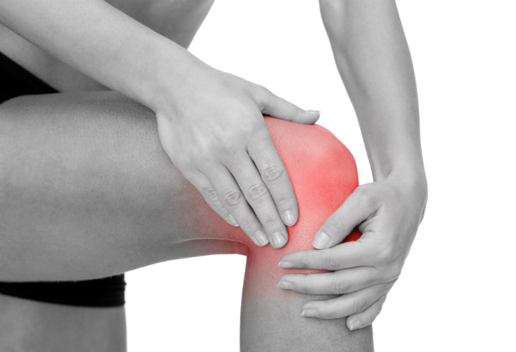 person holds their knee, which is red and suggesting a sore joint