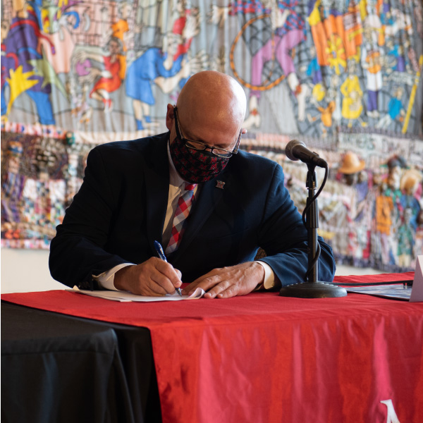President Gregory Crawford signing a memorandum of understanding at the Moon Shot for Equity press conference.