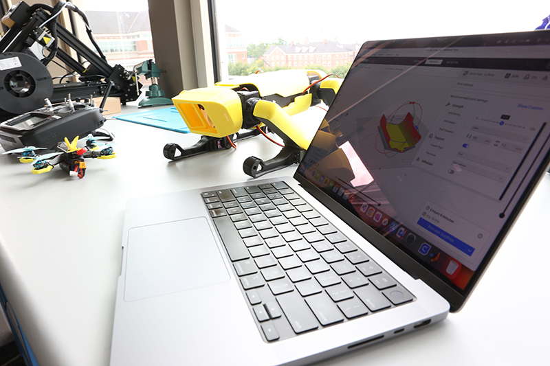 A laptop open on a table next to a drone