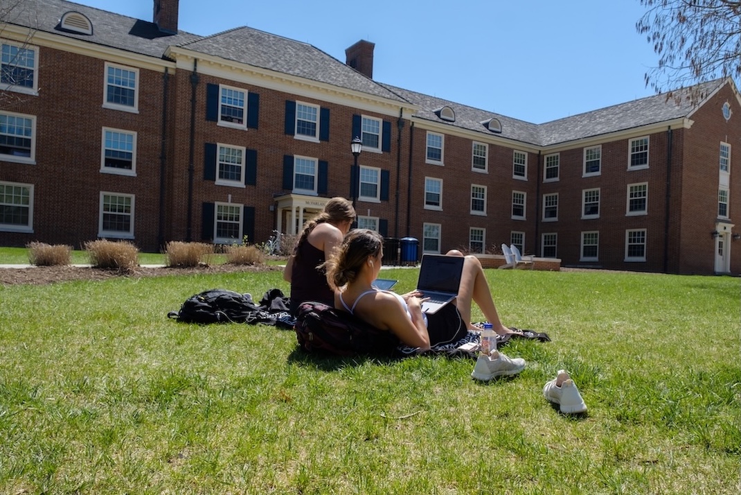 Students sitting outside on the lawn with their laptops