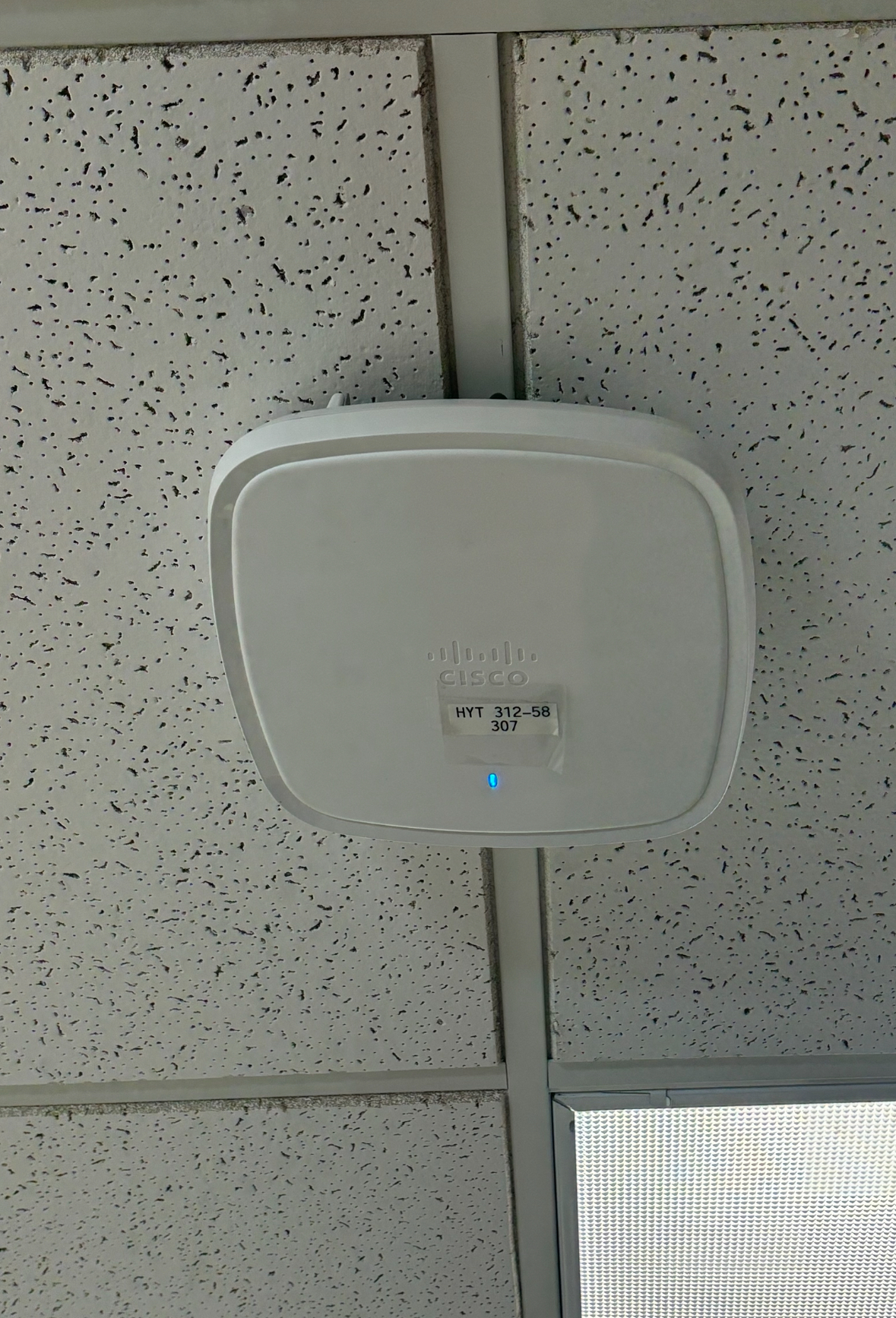 A white box hanging from the ceiling that is a Miami access point