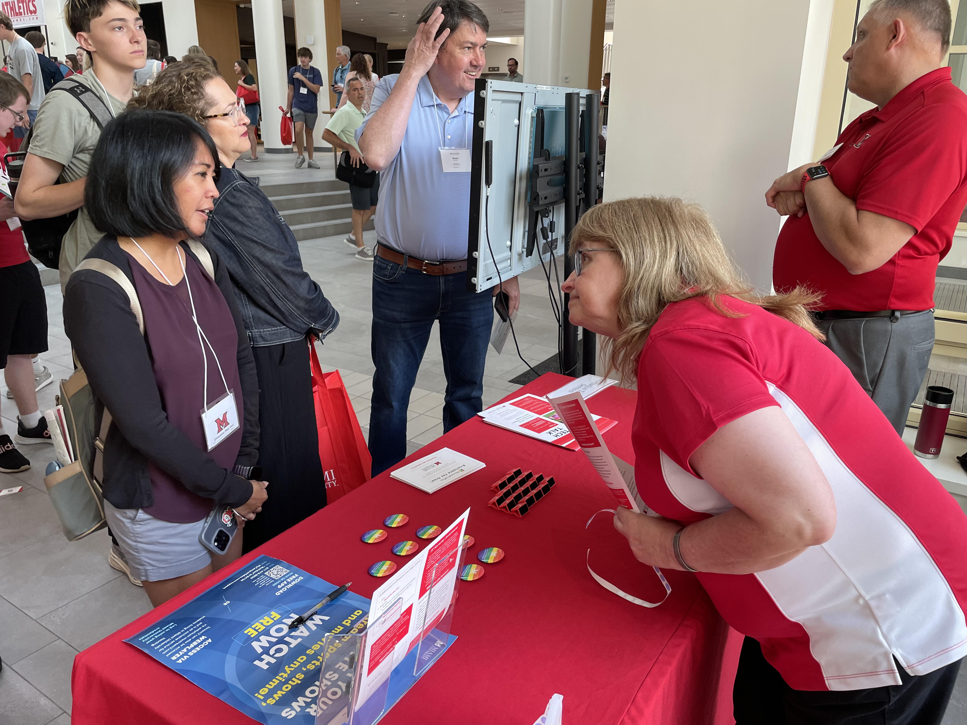 IT volunteer leaning over the resource fair table to help out a parent