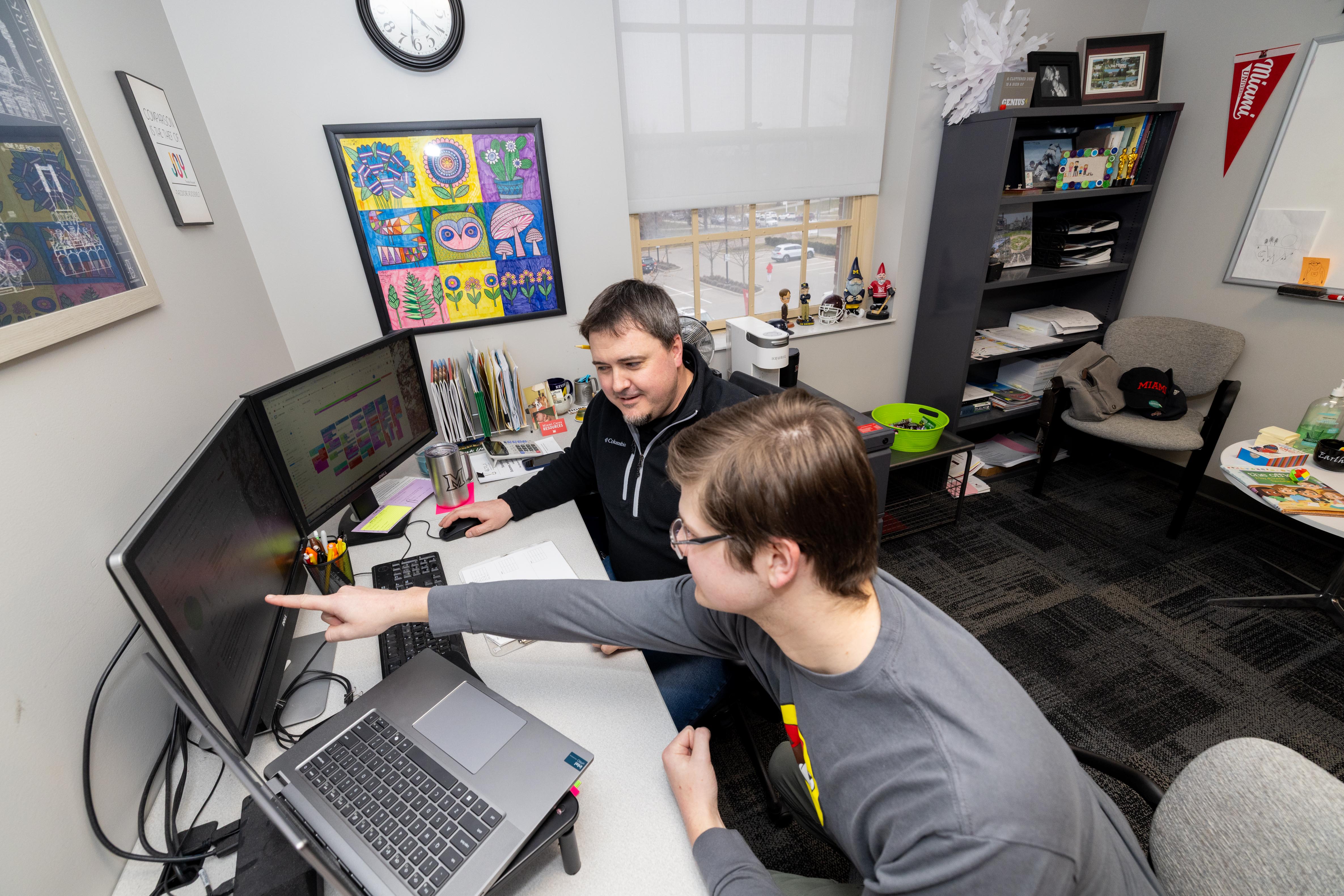 Two students analyzing graphs on various computer screens