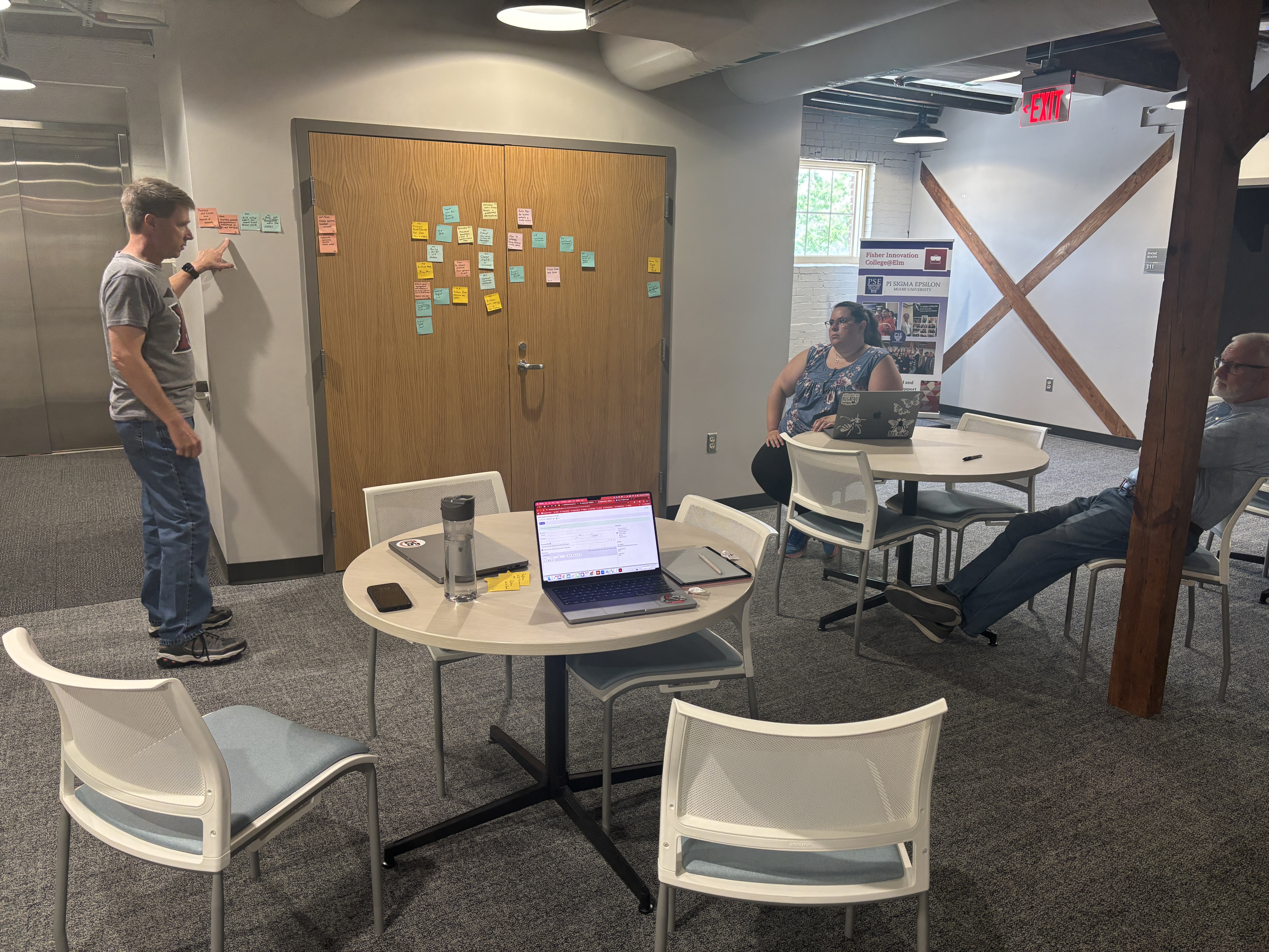 Dirk Tepe and Erin Mills talk about a wall of sticky notes 