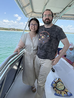 Ruowei and her husband stand on a boat over bright blue ocean waters