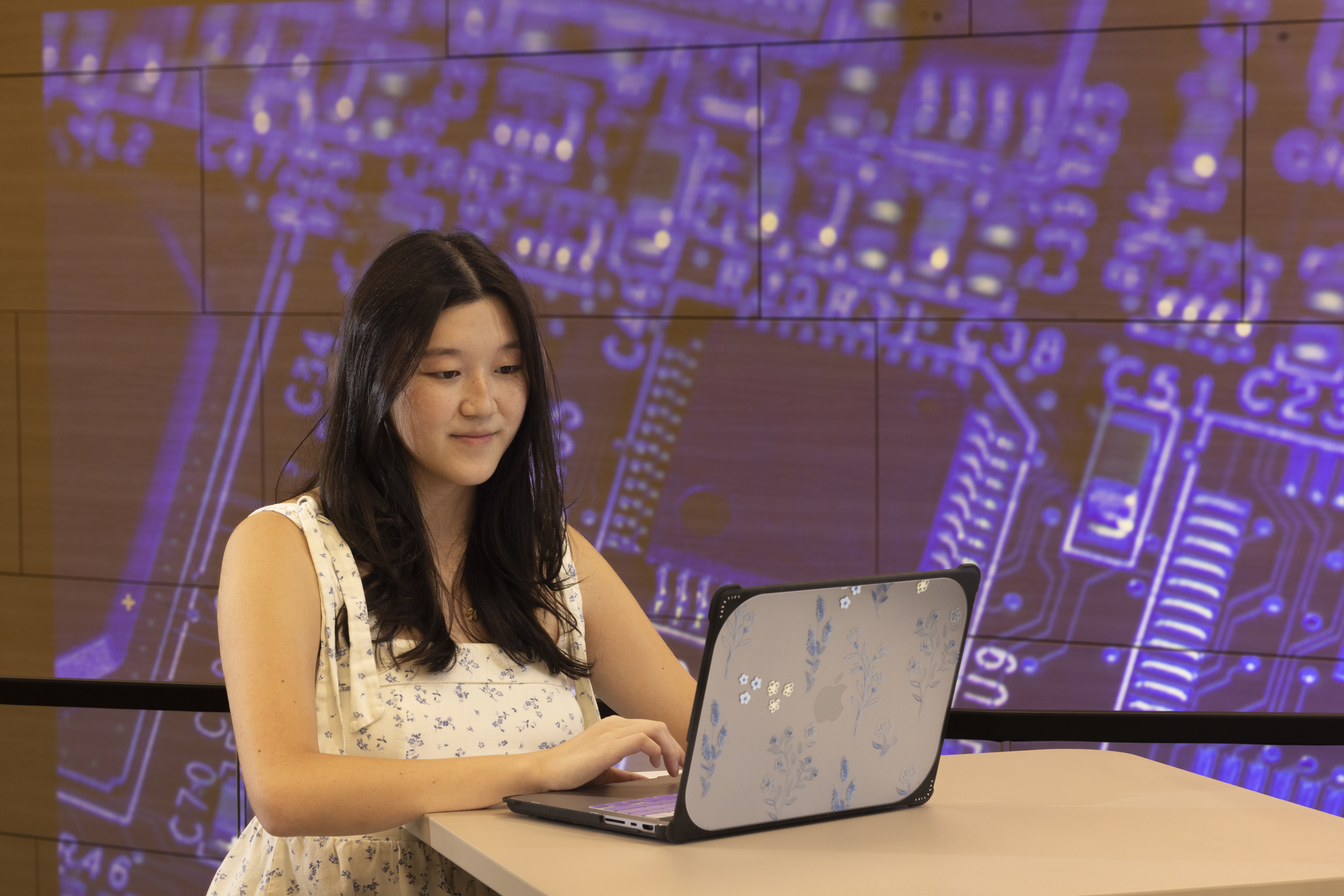 Computer graduate student serena owens standing in front of the XR stage with code in the background, looking at her laptop